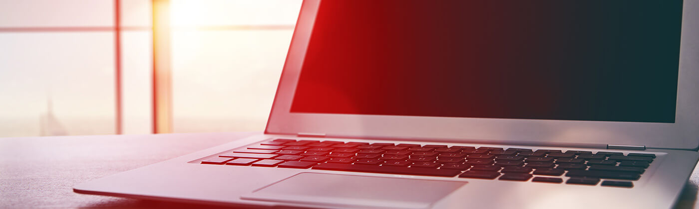 Tisch mit Laptop, im Hintergrund eine große Fensterfront